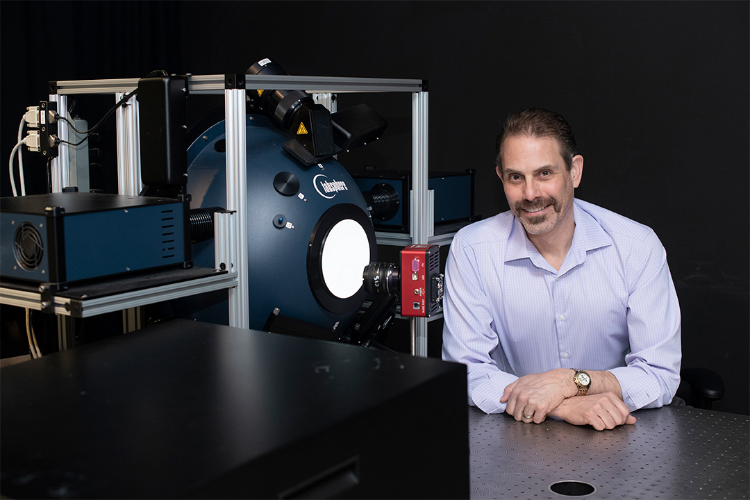 professor posing next to imaging equipment.