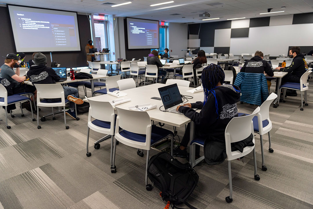 students sitting at desks working on computers in a large conference room.