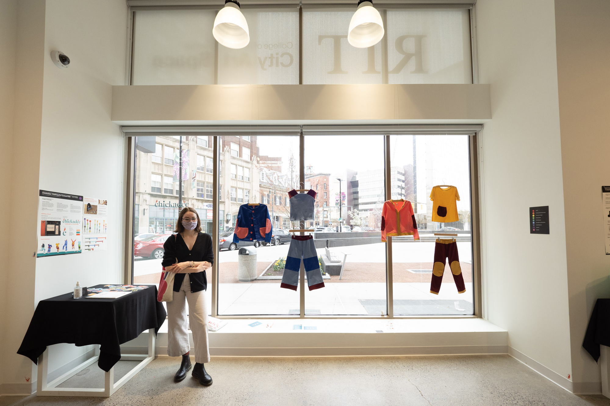 Daeya Shealy stands beside a display of the sustainable clothing line she designed in RIT City Art Space.