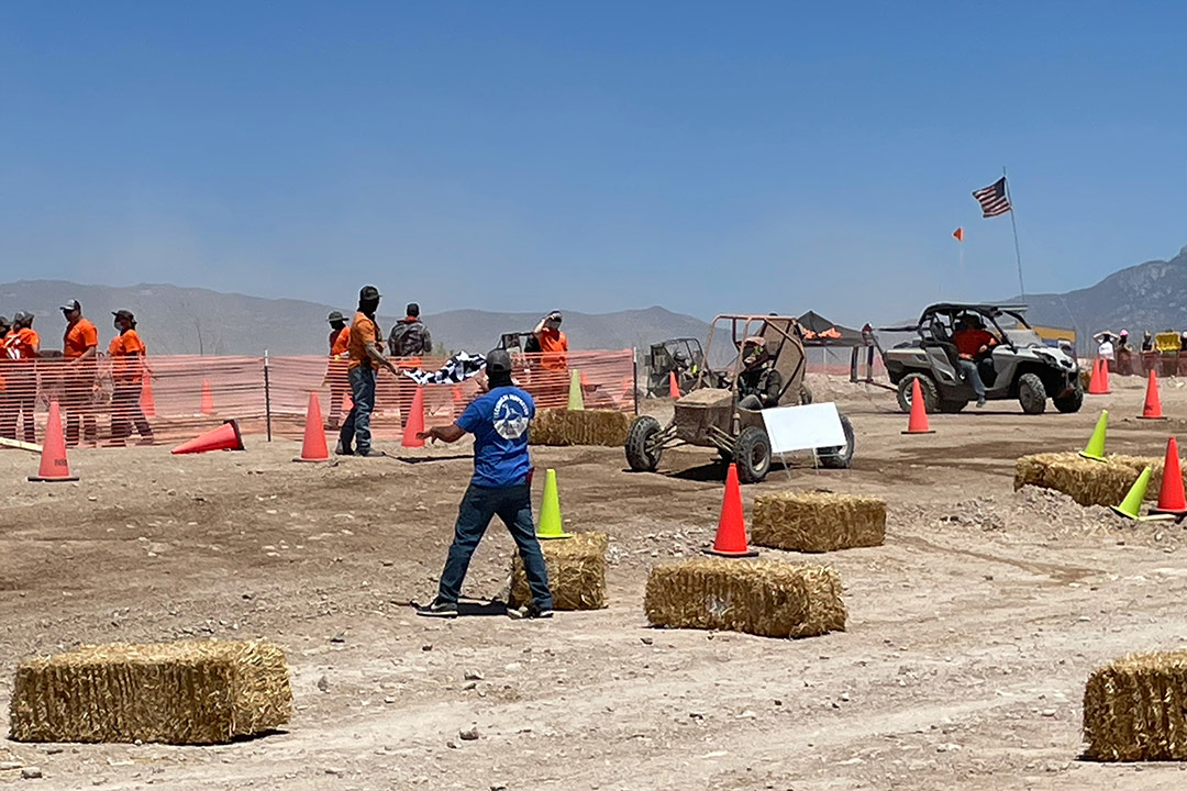 baja cars driving through maze of cones and hay stacks.