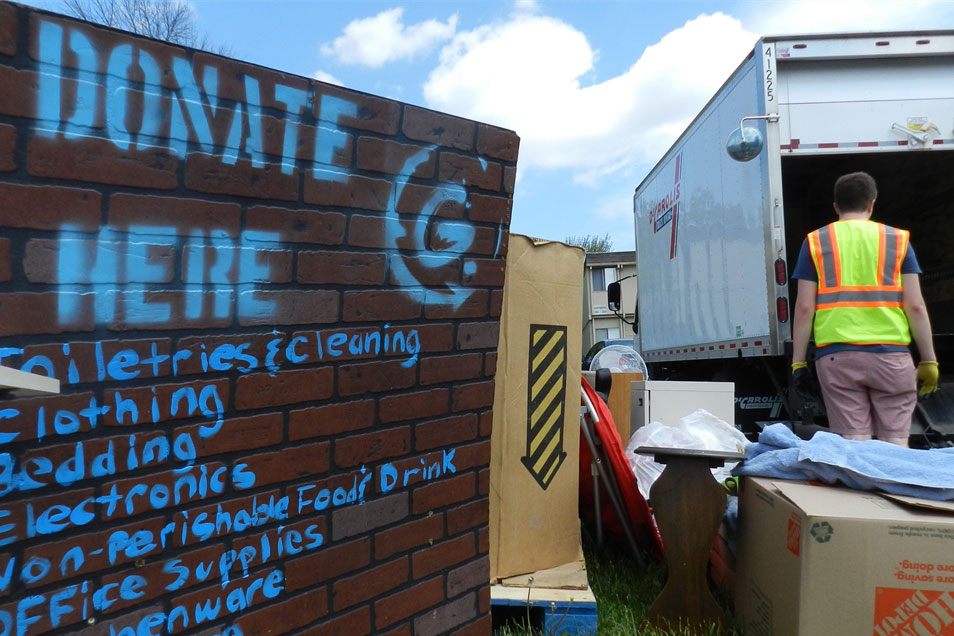 worker loading used items into a box truck next to sign that reads "Donate Here."