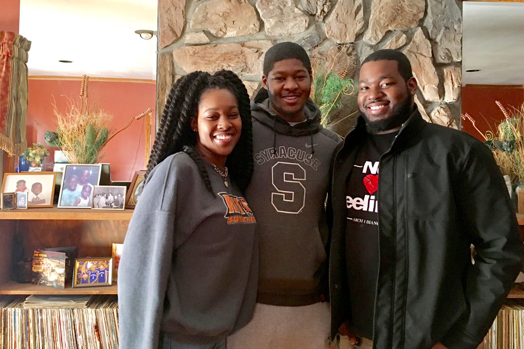 A group of three people posing for a photo in a living room.