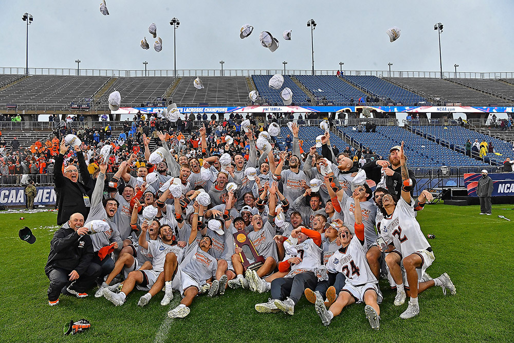 men's lacrosse team throwing hats into the air in celebration.