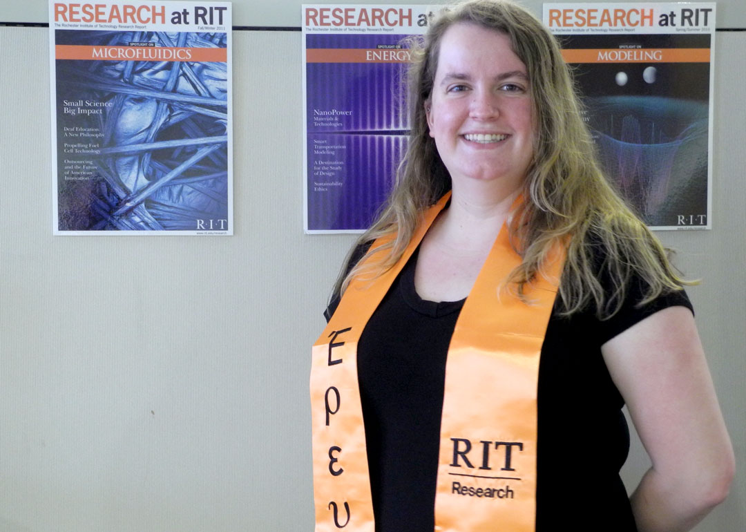 A woman wearing an orange sash with the words "RIT Research" embroidered on it in black.