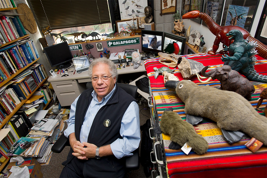 professor sitting in his office surrounded by information about the Galapagos.