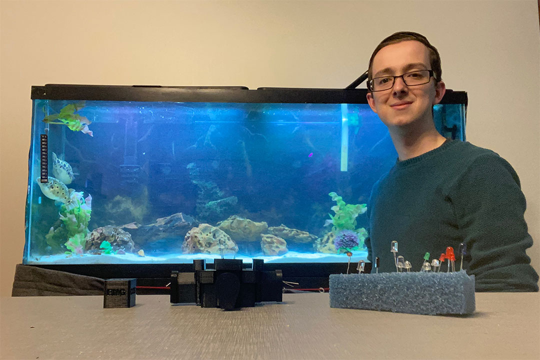 student posing with aquarium tank and homemade measuring equipment.