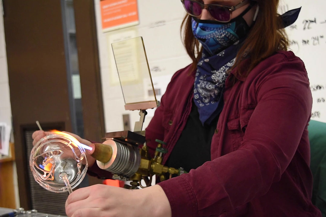 artist rotating a glass ball throw a flame.