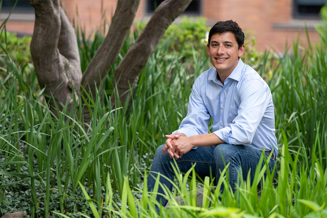 environmental portrait of Tony Wong sitting outdoors near a tree and tall grass.