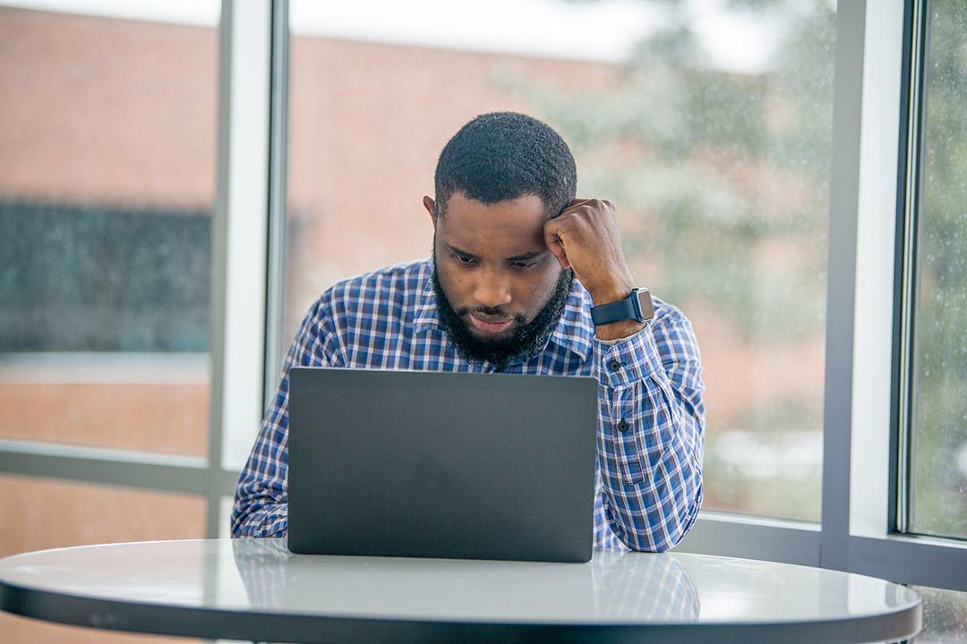 student sitting at a table working on a laptop computer.