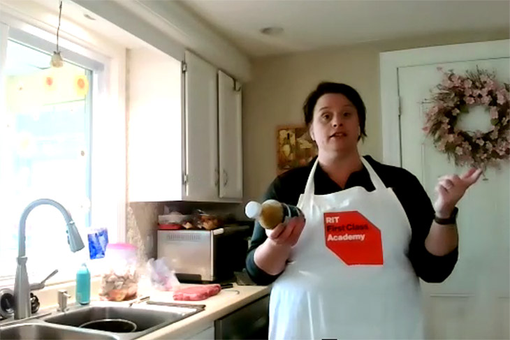 woman holding a jar of sauce standing in a kitchen.
