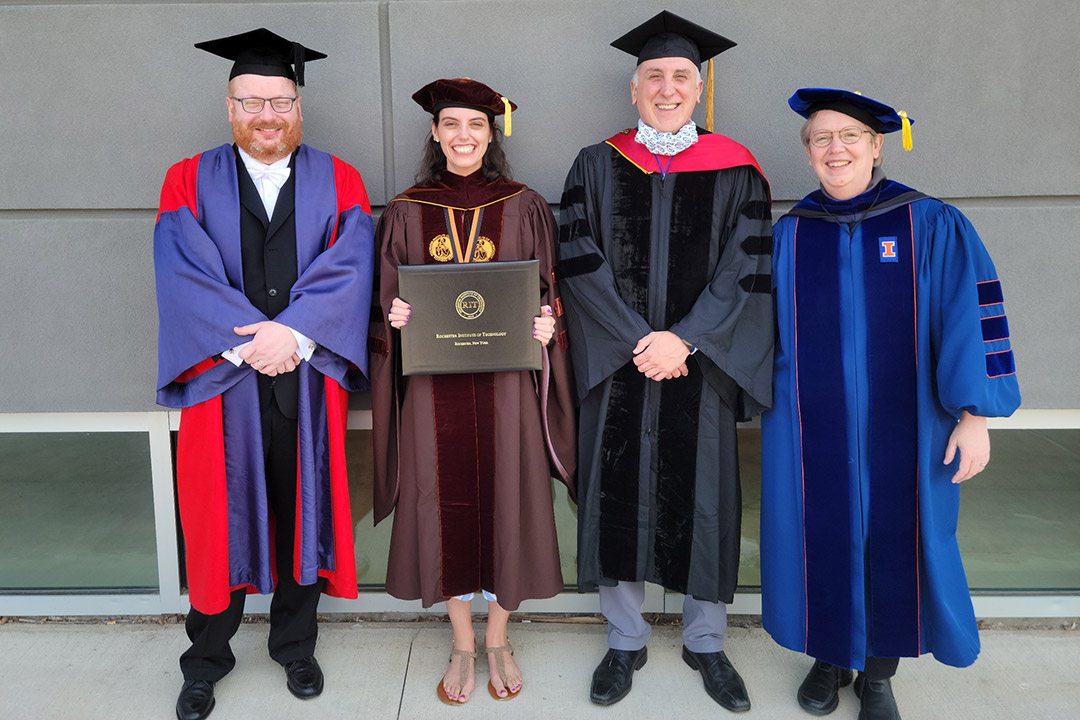 student and professors wearing graduation regalia.