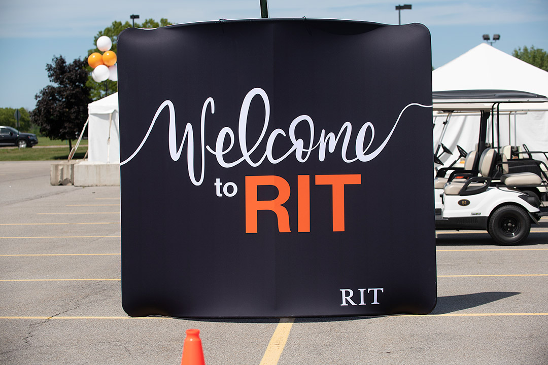 banner outdoors in a parking lot reads Welcome to RIT.