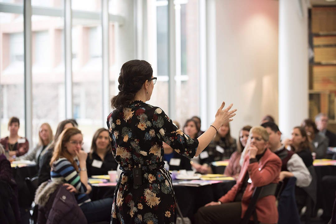 person standing in front of a room addressing a group of people.