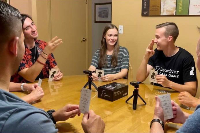 people sitting around a table playing a card game.