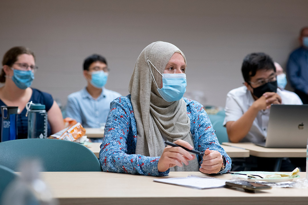 people wearing face masks seated at long tables attending a workshop.