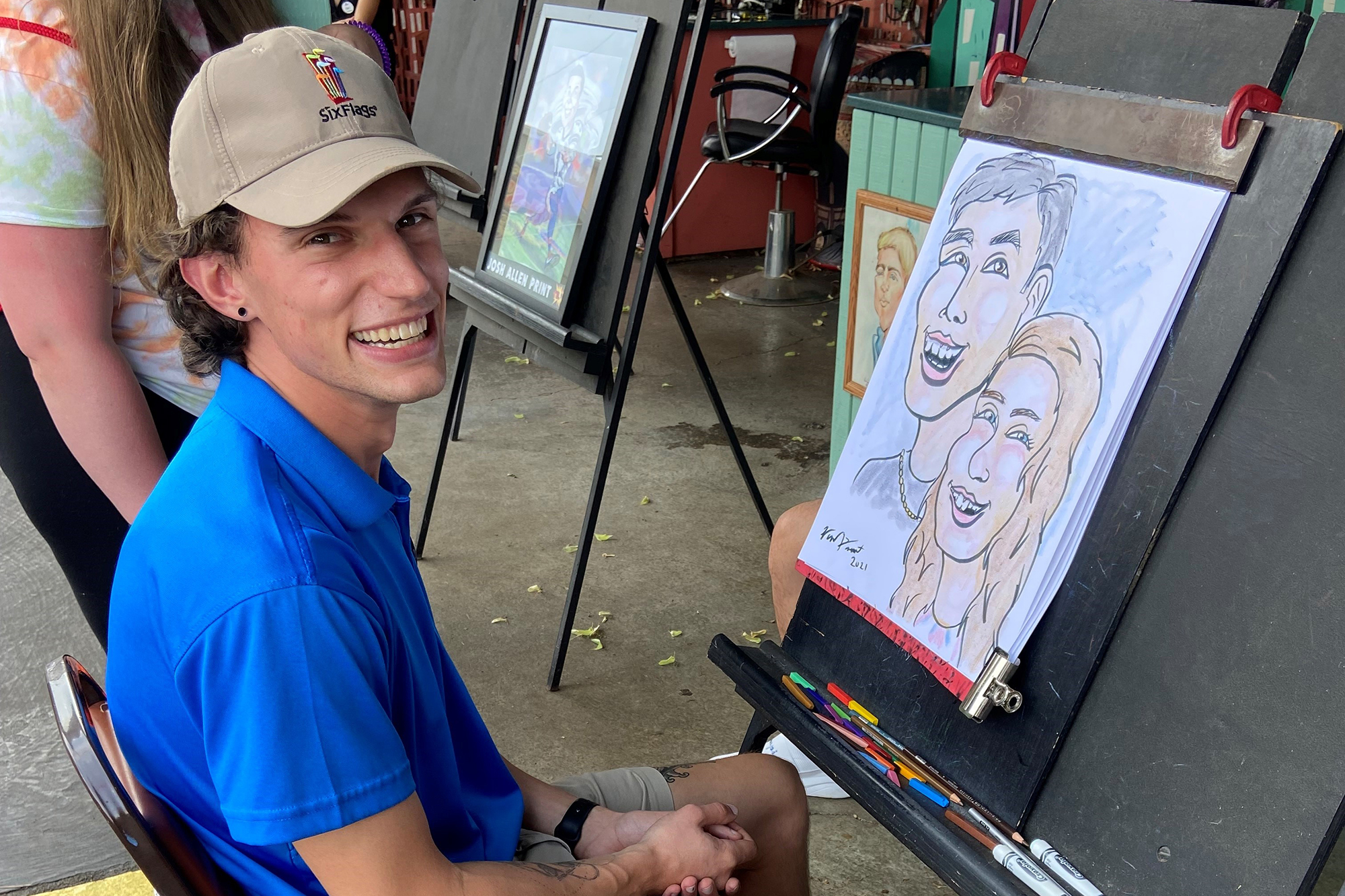 Zach Hildebrandt poses in front of a display caricatures at Six Flags Darien Lake.