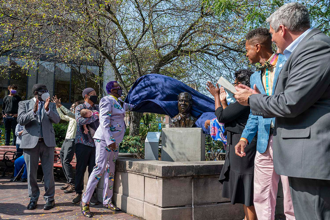 man pulling cover off of new statue.