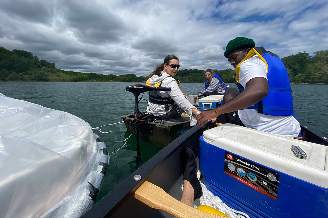 three researchers on a boat in a lake.