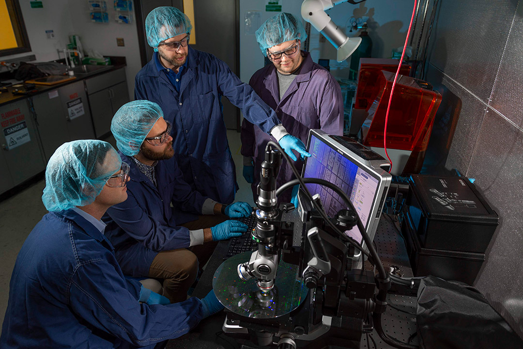 group of four scientists looking at a microchip.