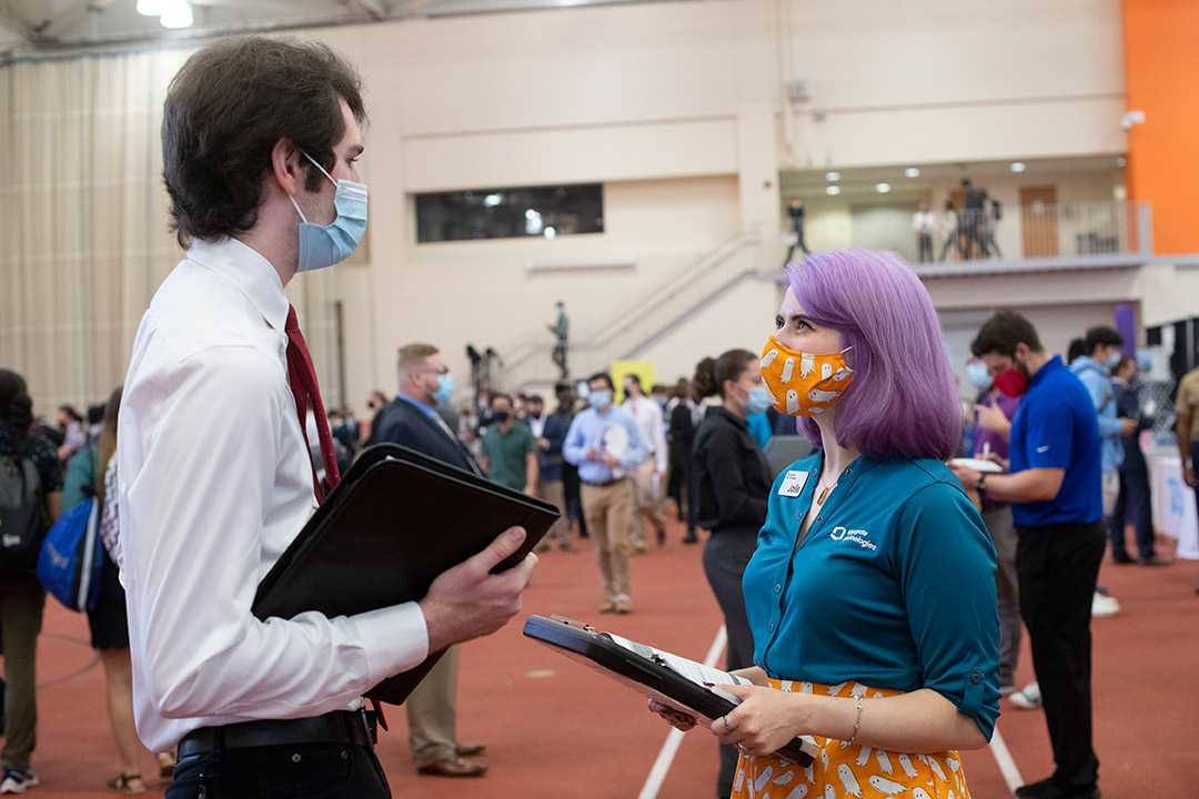 student and recruiter talking at a career fair.