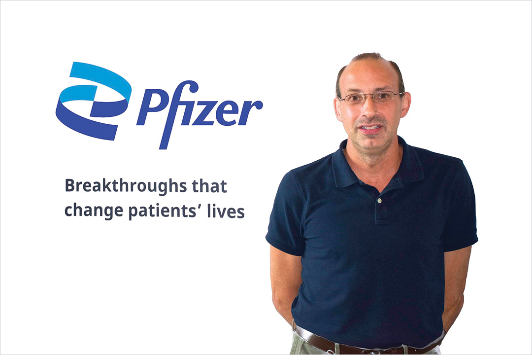 Christopher Vollaro standing next to the Pfizer logo.