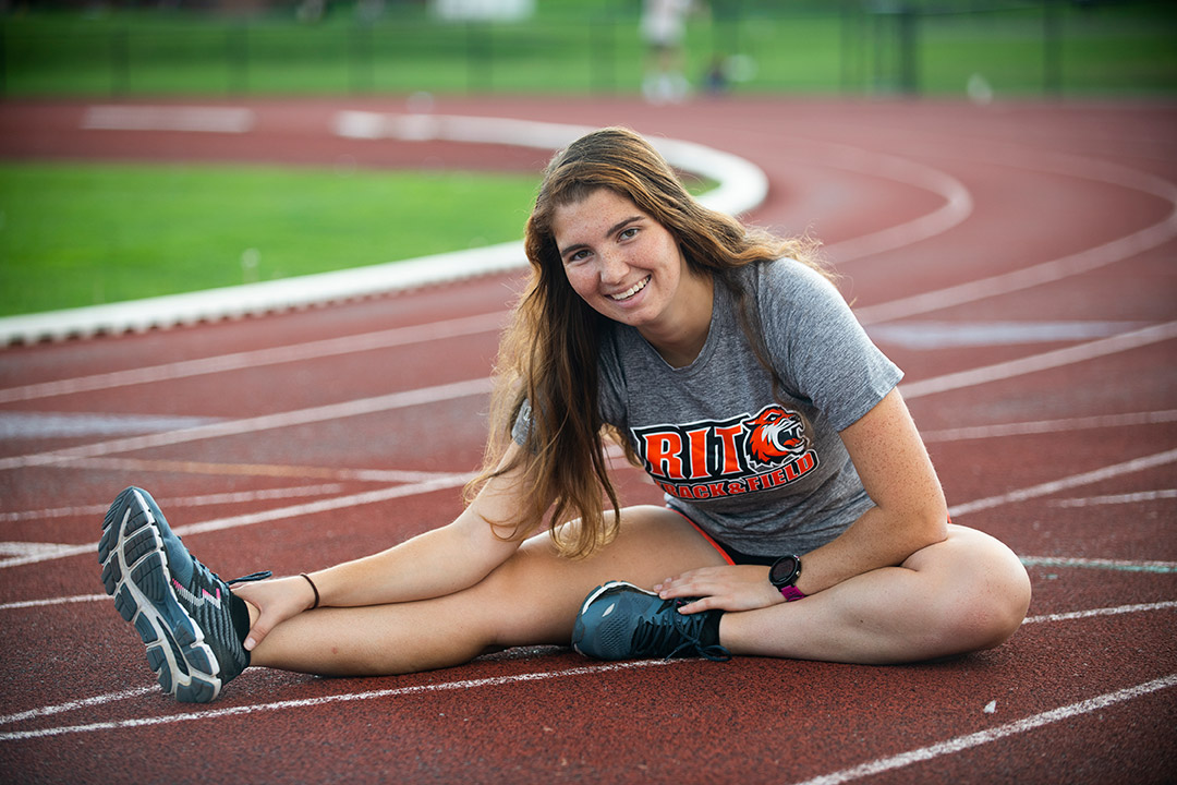 student-athlete stretching on an outdoor track.