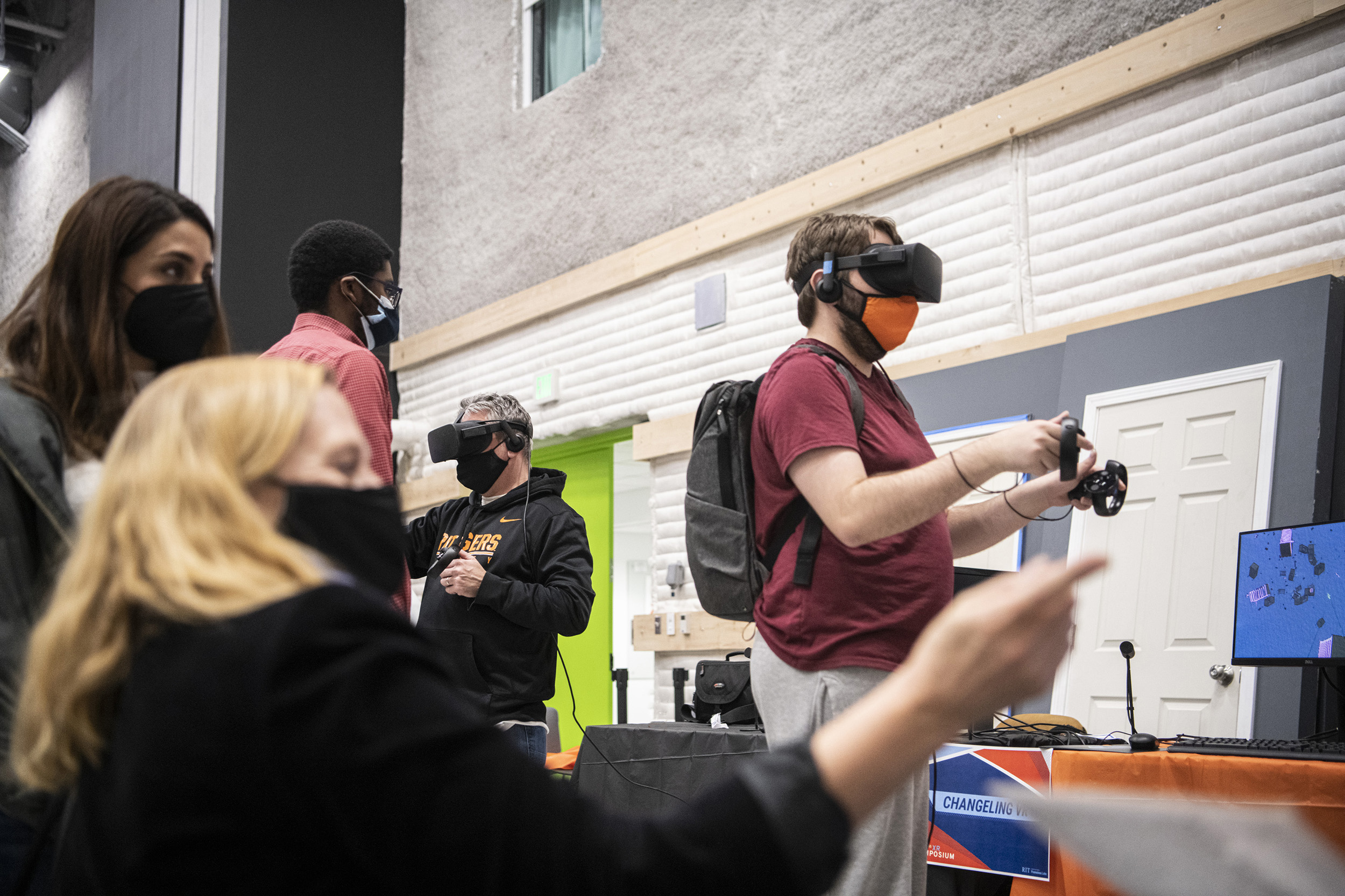 A group of people wearing VR headset demo various projects. 