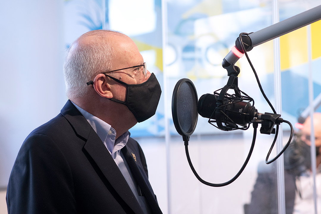 closeup of RIT President Munson talking into a radio station microphone.