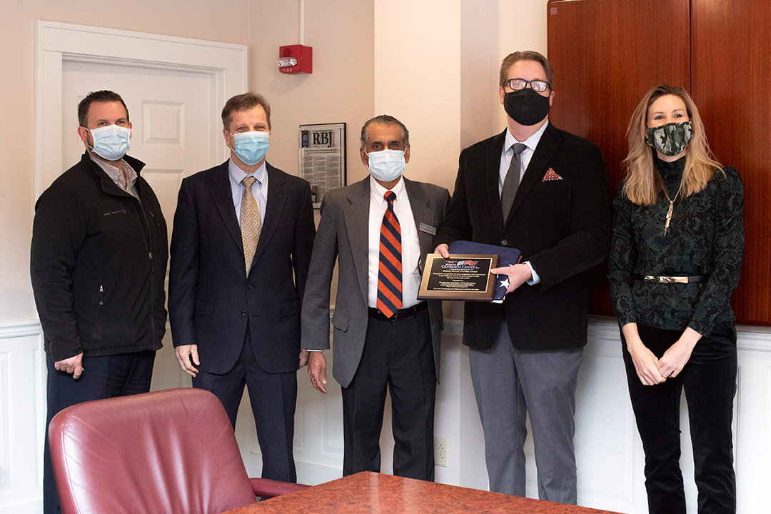 five people standing with one holding a plaque.