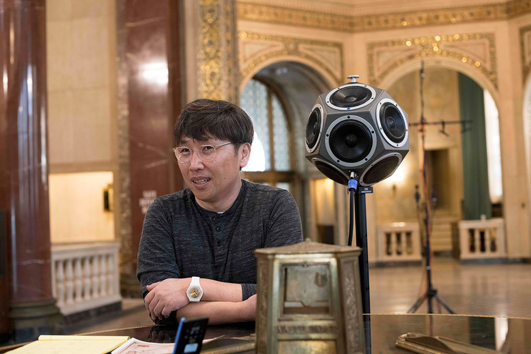 professor standing next to a multfacted speaker.