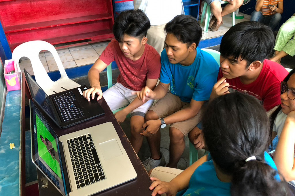 children in the Philippines looking at two laptop computers.