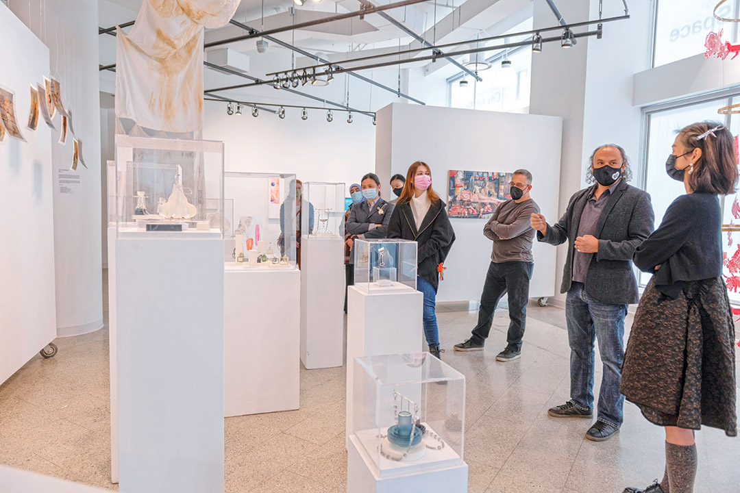 people in an art gallery looking at jewelry and prints.