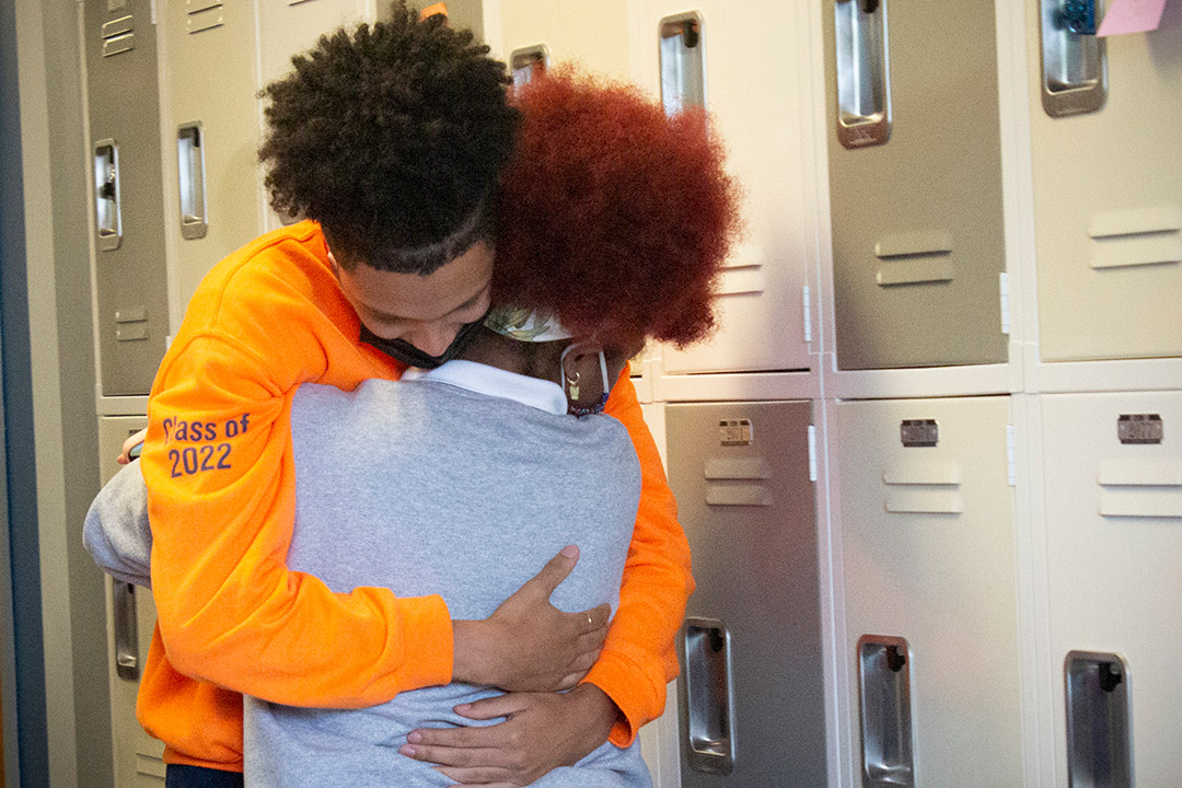 two students hugging in front of school lockers.