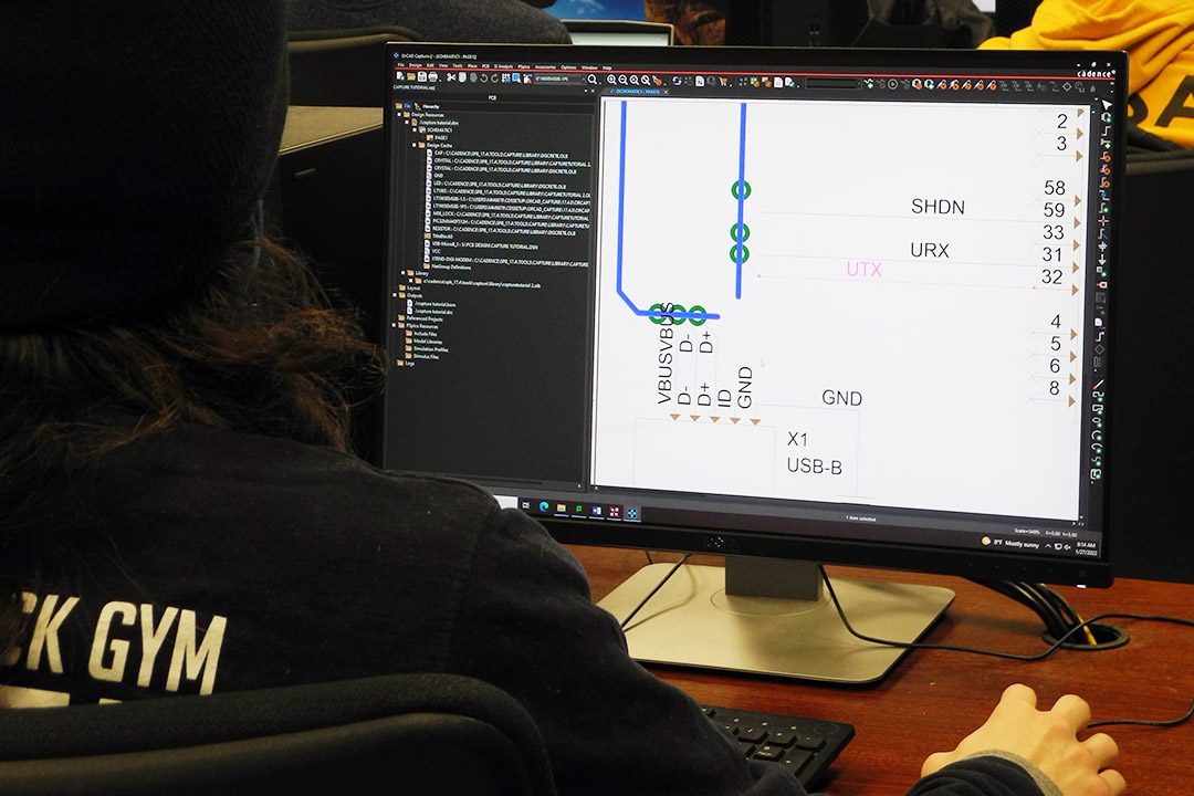 student designing a printed circuit board on a computer.