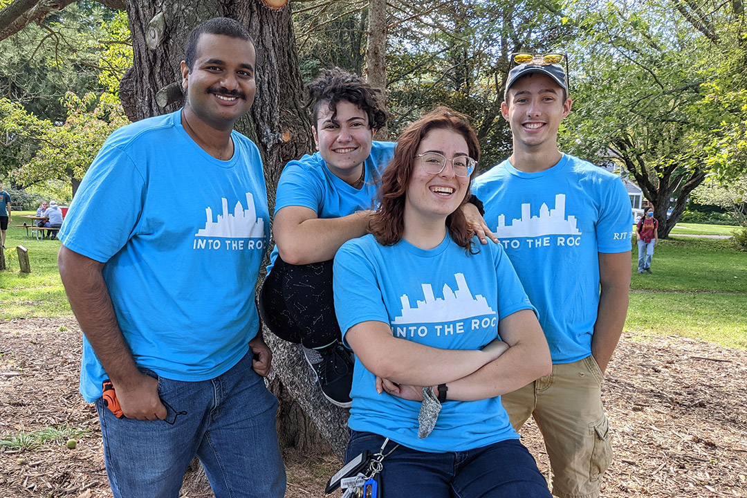 four student volunteers posing for a photo on a tree branch.