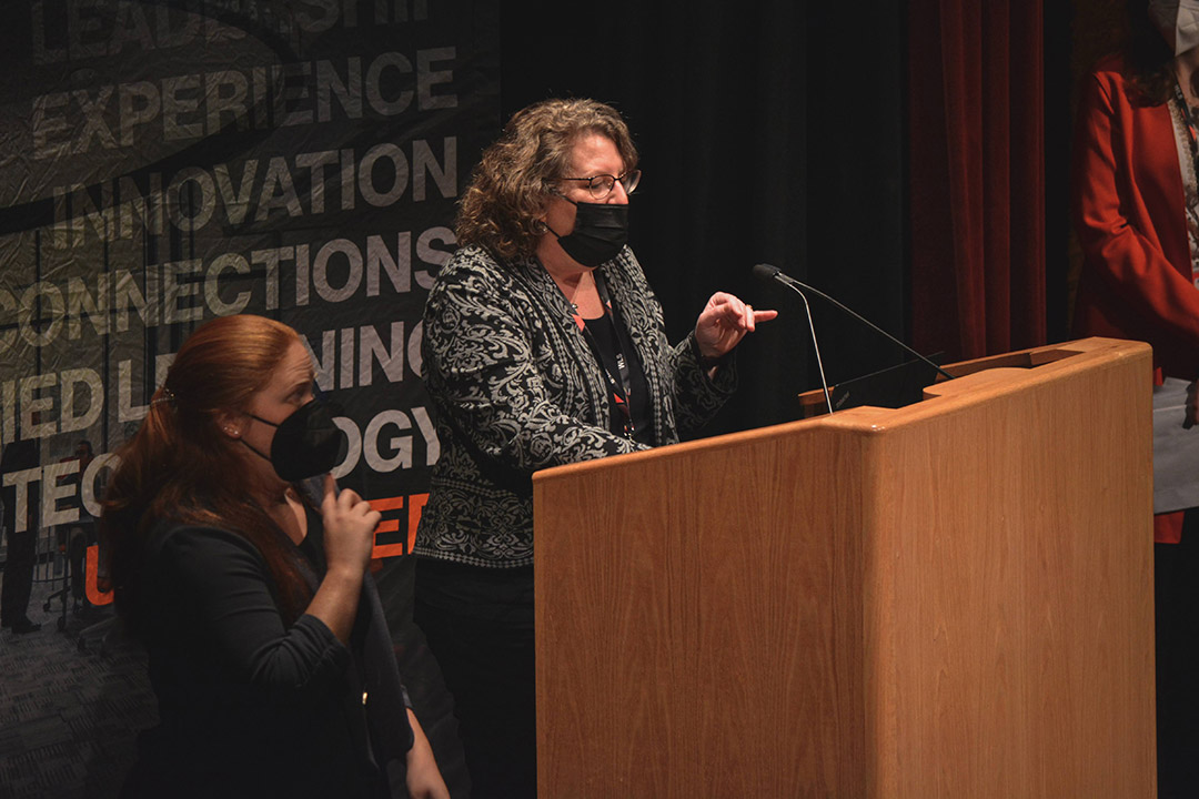 woman speaking at a podium with a sign language interpreter next to her.