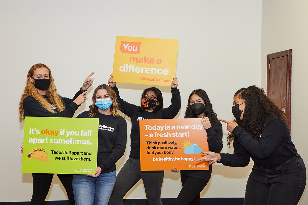 group of five students holding signs with encouraging phrases.