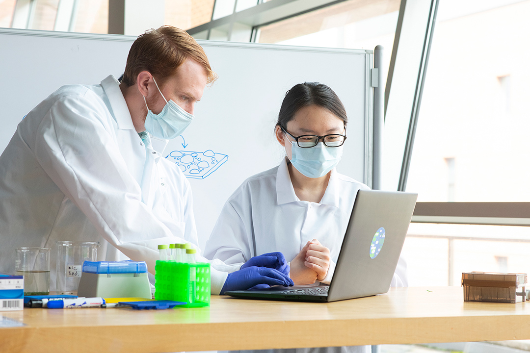 two students working on a laptop in a lab.