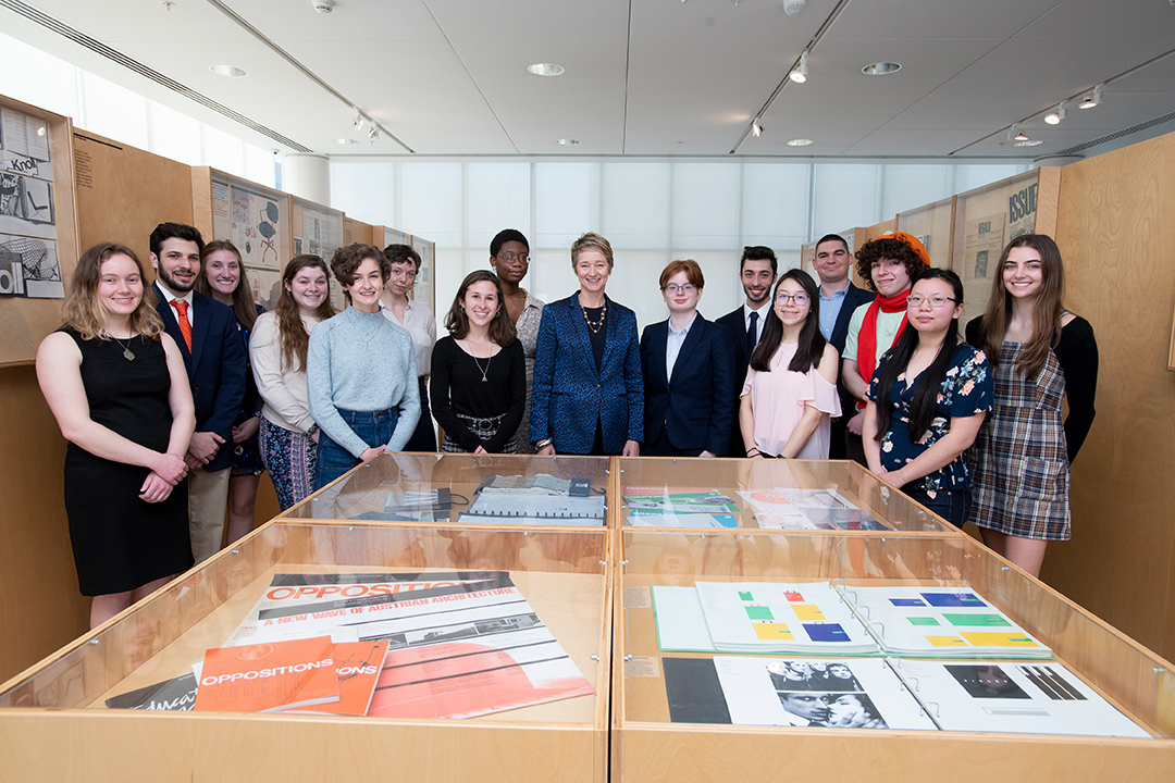 group of students standing with dean near a display of magazine and writing samples.