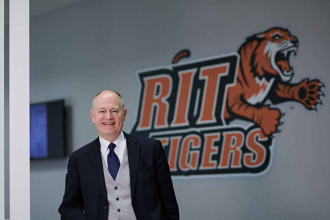 RIT Croatia Dean Don Hudspeth standing in front of an RIT Tigers logo.