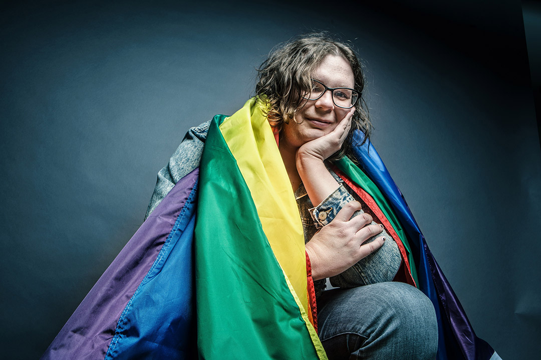 student Emily Horton with a rainbow flag draped around her shoulders.