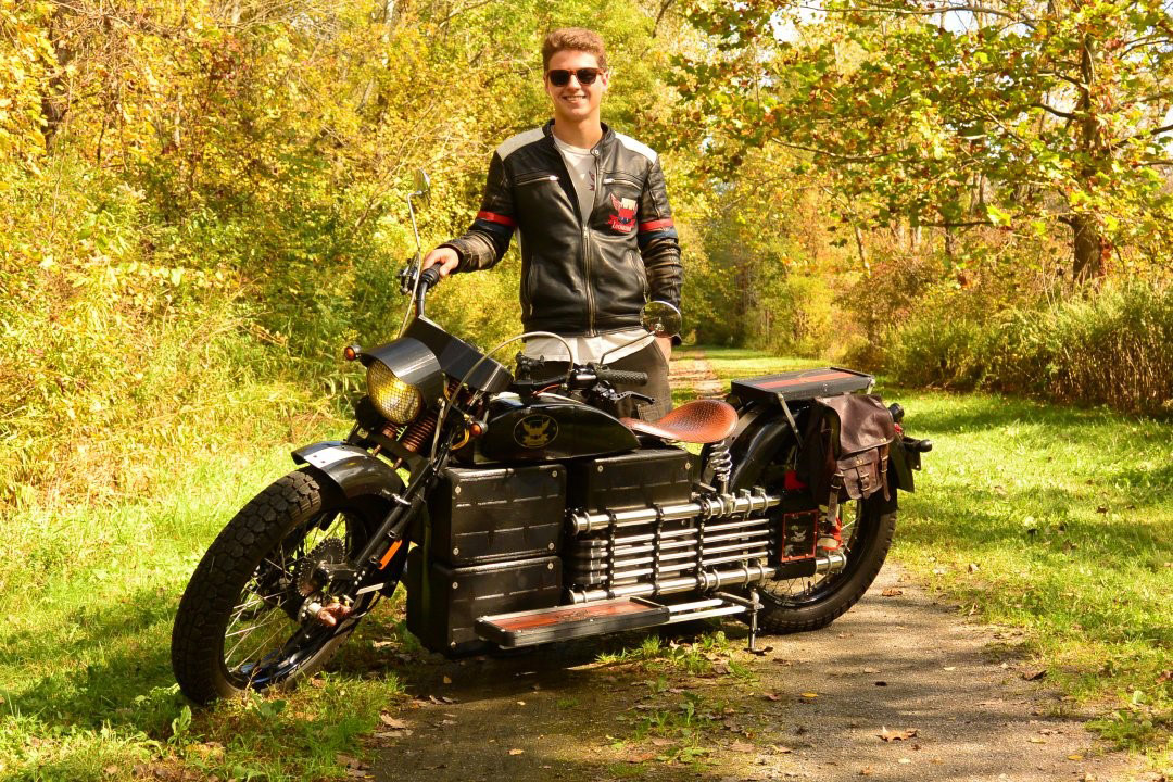 student standing with a motorcycle.