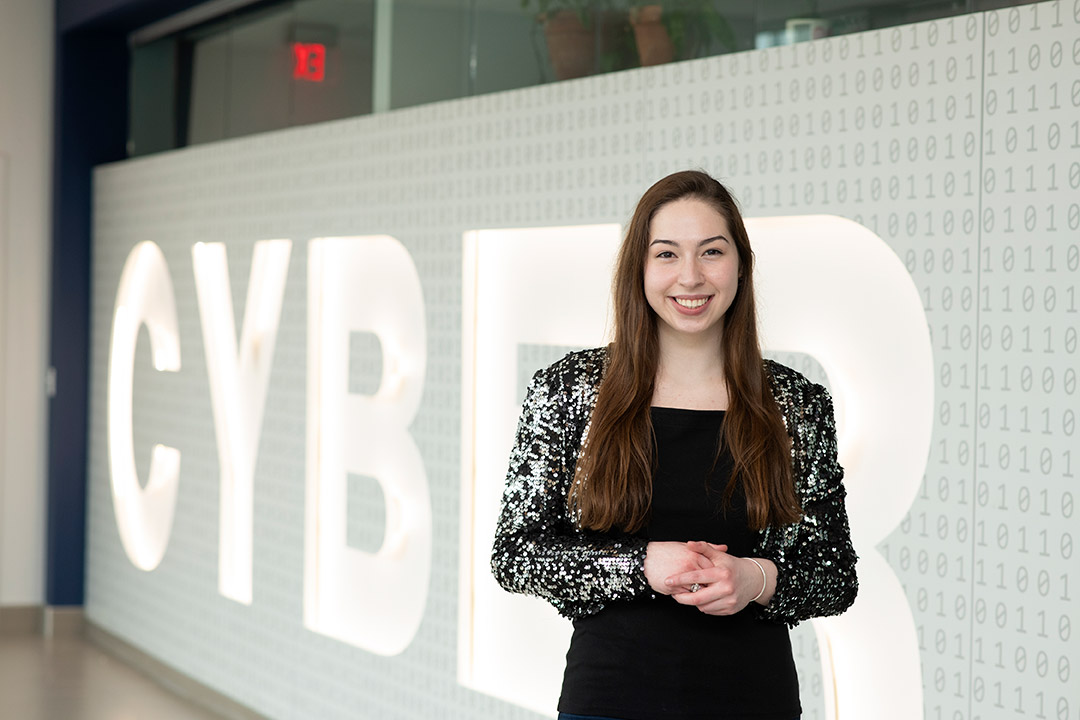 student Olivia Gallucci standing in front of a large cyber sign.