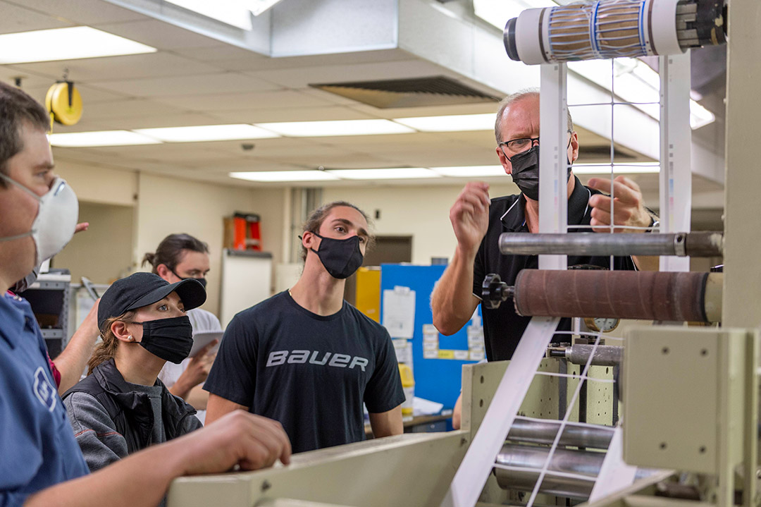 students and professor watching a printing machine.