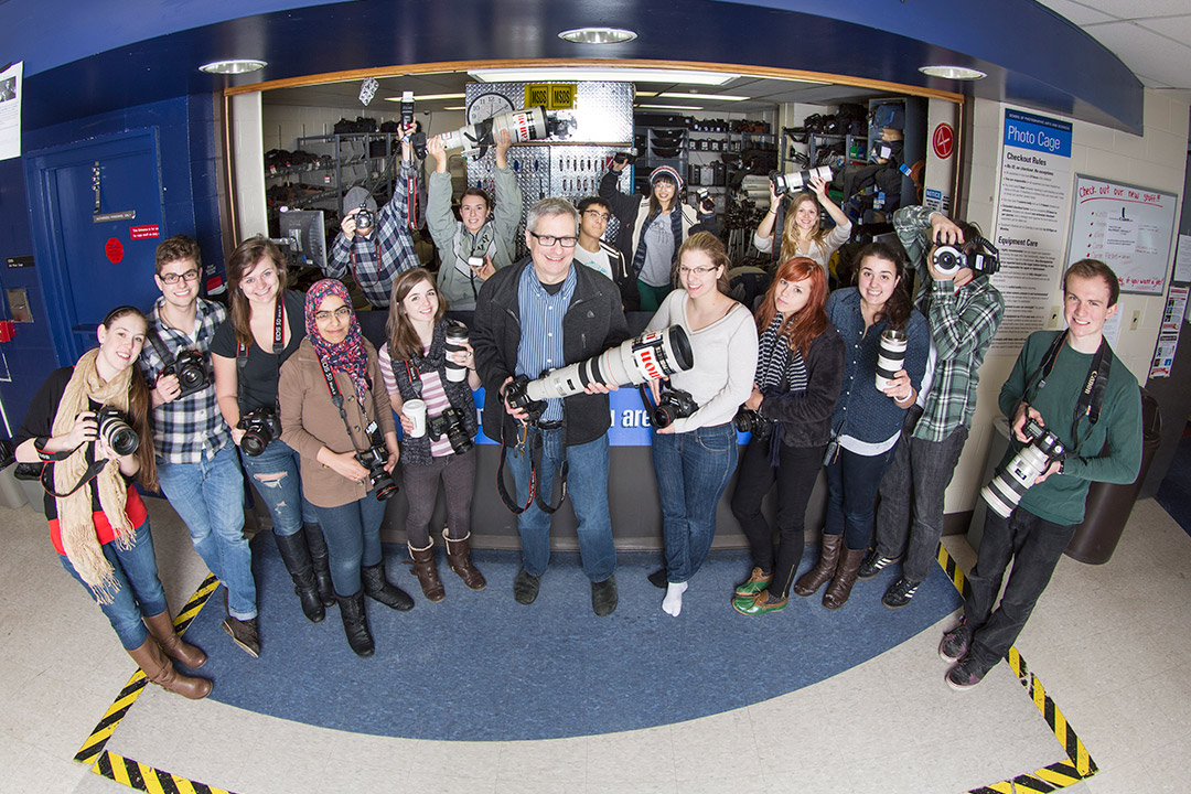 group of students holding cameras with their professor standing in the middle.