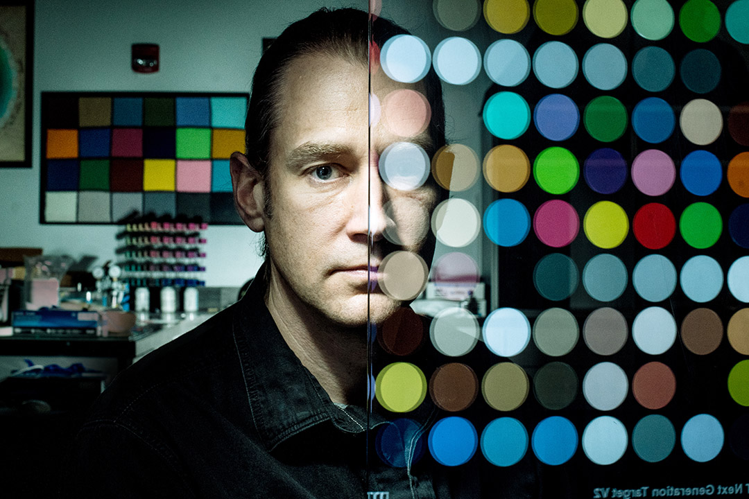 portrait of professor with glass pane with colored polka dots covering half of his face.