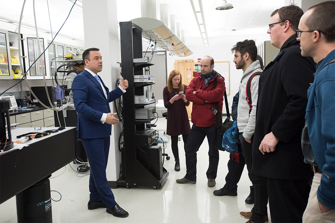 man leads a tour of a photonics lab.