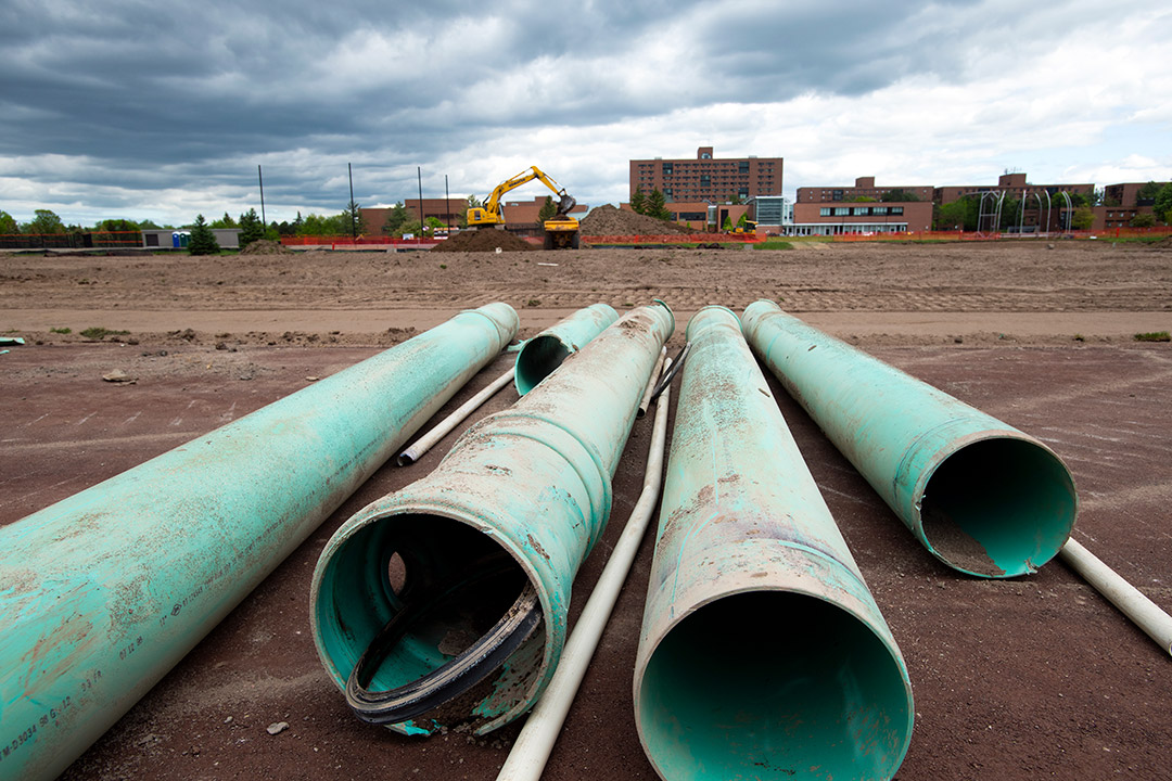 pieces of pipe laying on the ground near a building construction site.