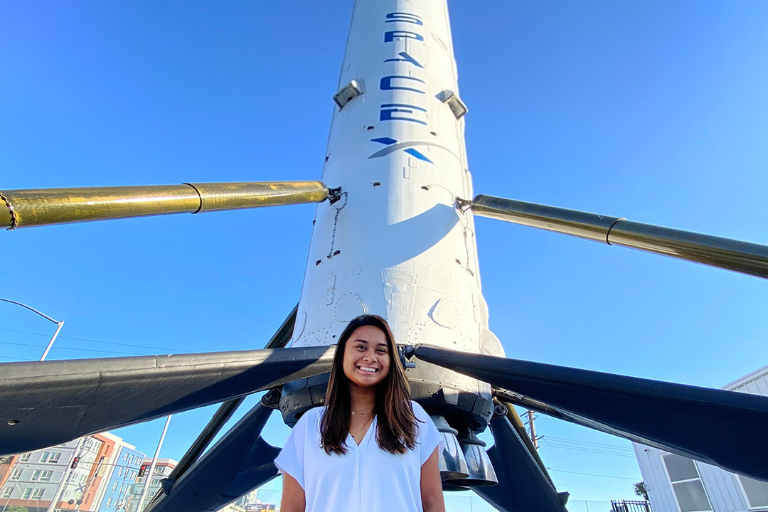 student standing in front of a SpaceX rocket.