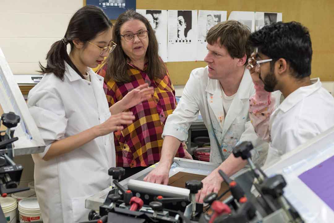 professor and three students working with lab equipment.